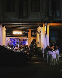 a group of people standing outside a restaurant at night