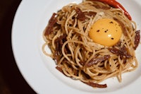 a plate of spaghetti with an egg on top